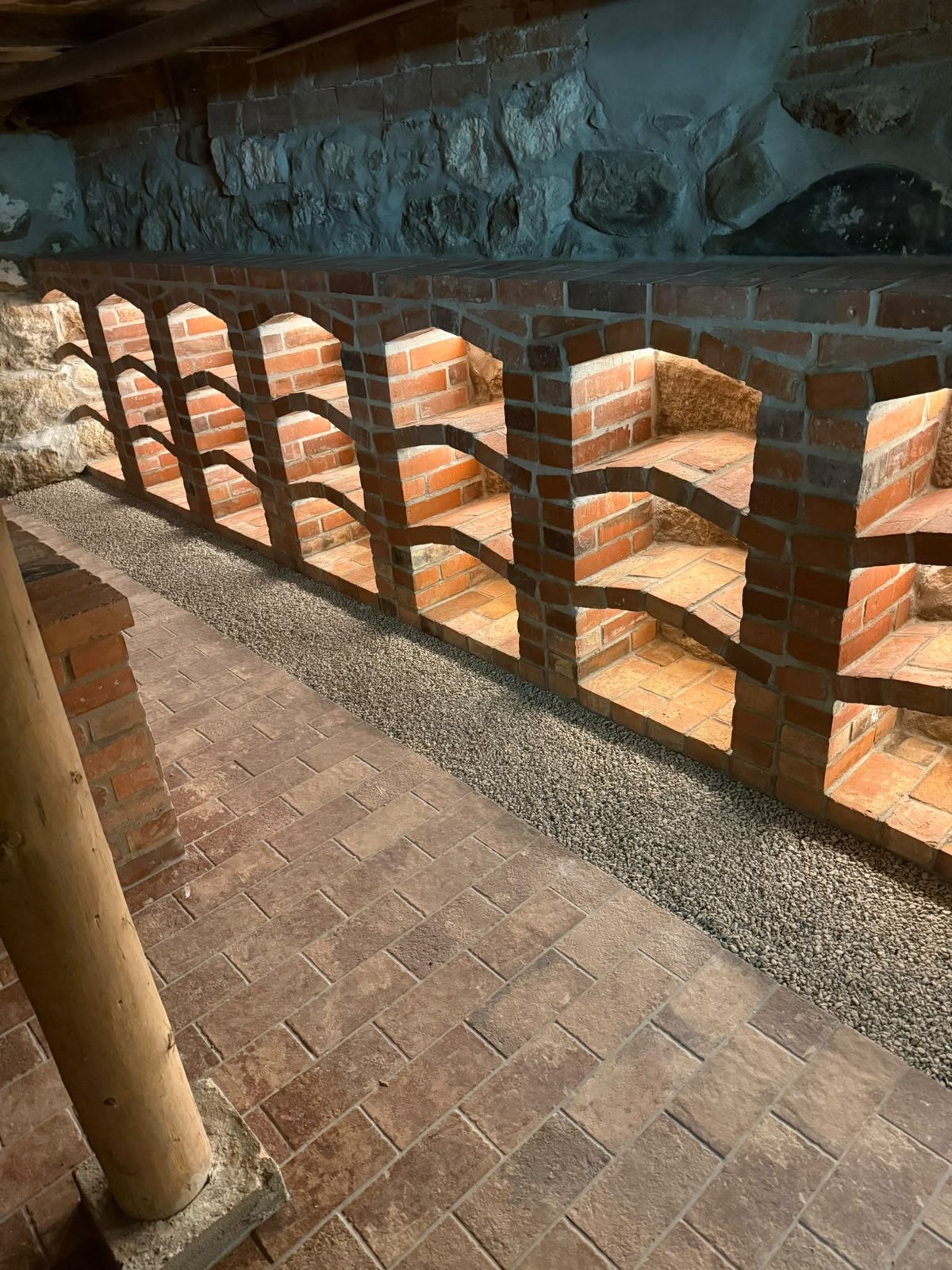 Gemauerte Ziegelbögen vor der Natursteinwand nach der Kellersanierung